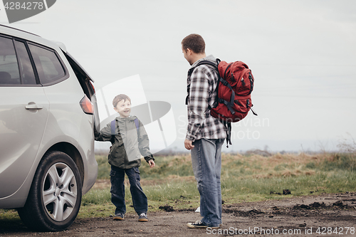 Image of Father and son walking on the road at the day time.