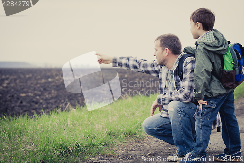 Image of Father and son walking on the road at the day time.