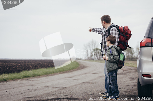 Image of Father and son walking on the road at the day time.