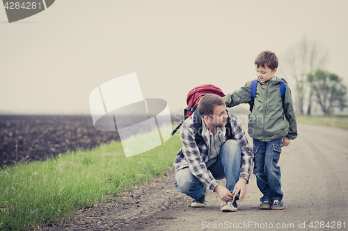 Image of Father and son walking on the road at the day time.