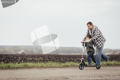 Image of Father and son walking on the road at the day time.