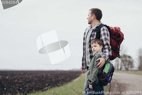 Image of Father and son walking on the road at the day time.