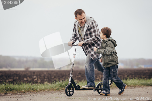 Image of Father and son walking on the road at the day time.