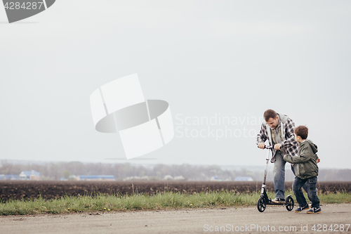 Image of Father and son walking on the road at the day time.