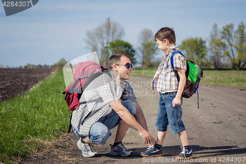 Image of Father and son walking on the road at the day time.