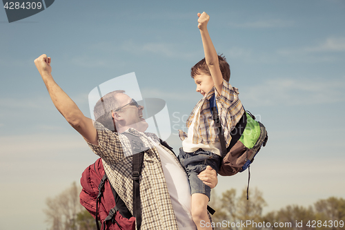 Image of Father and son walking on the road at the day time.