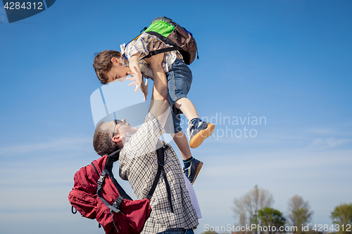 Image of Father and son walking on the road at the day time.