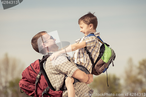 Image of Father and son walking on the road at the day time.