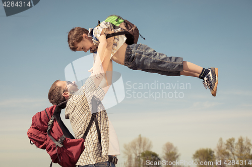 Image of Father and son walking on the road at the day time.