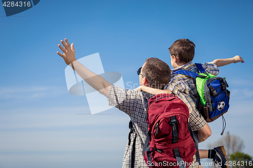 Image of Father and son walking on the road at the day time.