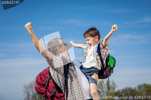 Image of Father and son walking on the road at the day time.