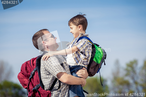 Image of Father and son walking on the road at the day time.