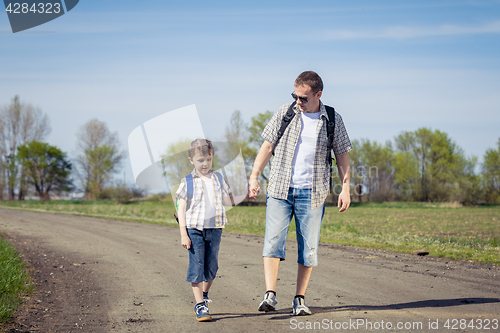 Image of Father and son walking on the road at the day time. 