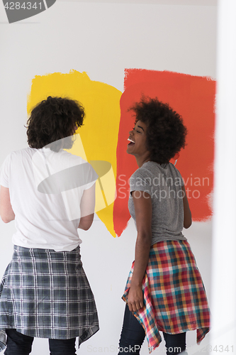 Image of multiethnic couple painting interior wall