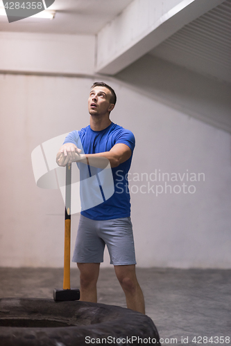 Image of man workout with hammer and tractor tire