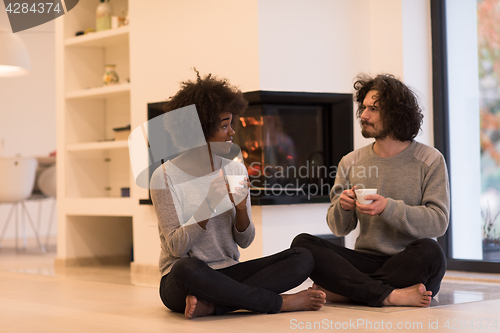 Image of multiethnic couple  in front of fireplace