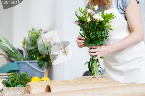 Image of Young woman florist makes bouquet