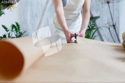 Image of Woman florist cuts wrapping paper