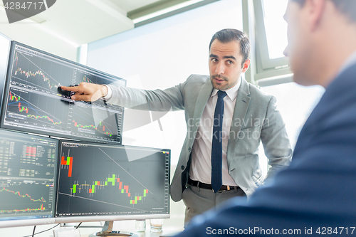 Image of Stock brokers looking at computer screens, trading online.