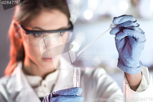 Image of Young scientist pipetting in life science laboratory.