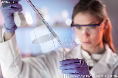 Image of Young scientist pipetting in life science laboratory.