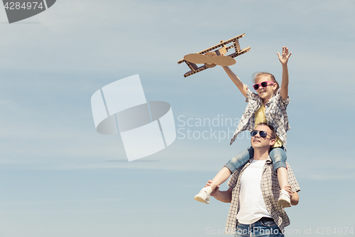 Image of Father and daughter playing with cardboard toy airplane in the p