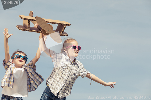 Image of Little kids playing with cardboard toy airplane in the park at t