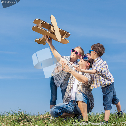 Image of Father and children playing with cardboard toy airplane in the p