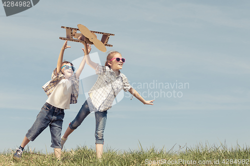 Image of Little kids playing with cardboard toy airplane in the park at t