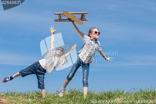 Image of Little kids playing with cardboard toy airplane in the park at t