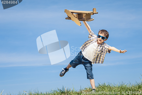 Image of Little boy playing with cardboard toy airplane in the park at th