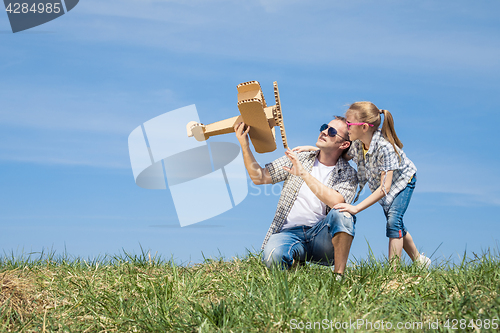 Image of Father and daughter playing with cardboard toy airplane in the p