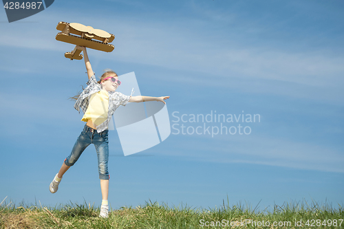 Image of Little girl playing with cardboard toy airplane in the park at t