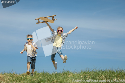 Image of Little kids playing with cardboard toy airplane in the park at t