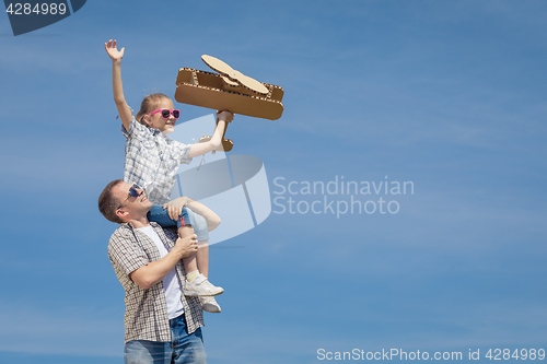 Image of Father and daughter playing with cardboard toy airplane in the p