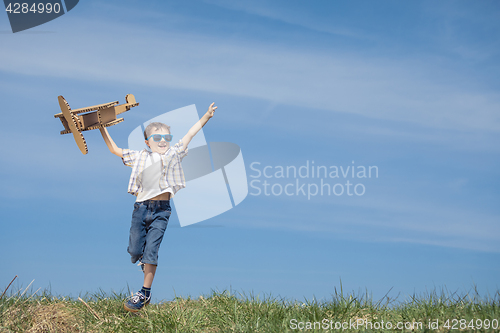 Image of Little boy playing with cardboard toy airplane in the park at th