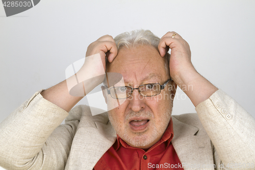 Image of White haired senior with glasses tearing his hair