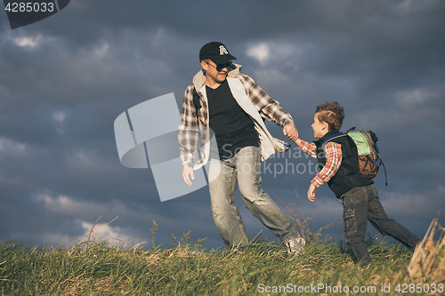 Image of Father and son walking on the road at the day time.