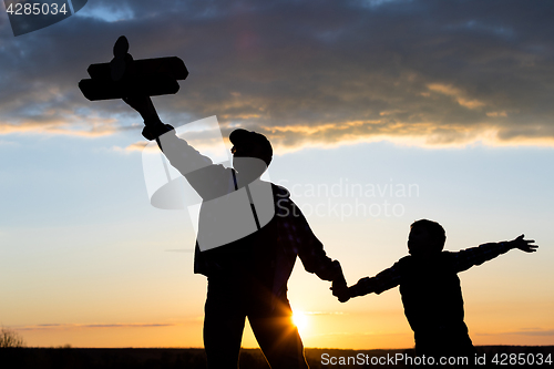 Image of Father and son playing with cardboard toy airplane in the park a