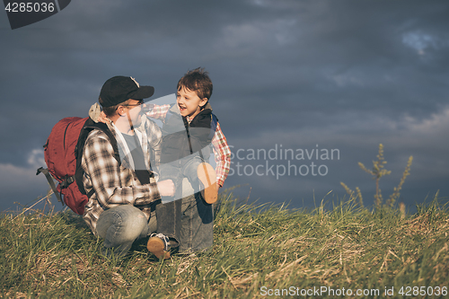 Image of Father and son walking on the road at the day time.