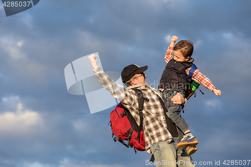 Image of Father and son walking on the road at the day time.