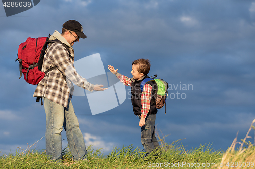 Image of Father and son walking on the road at the day time.