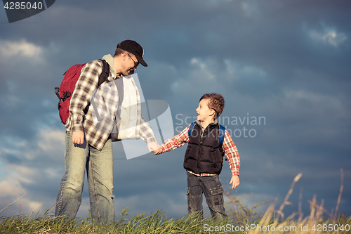 Image of Father and son walking on the road at the day time.