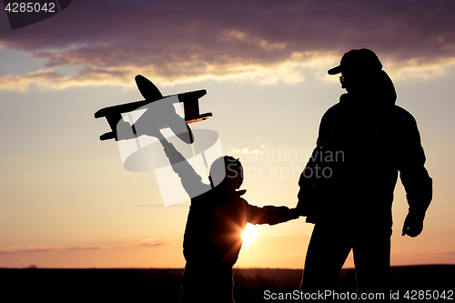 Image of Father and son playing with cardboard toy airplane in the park a