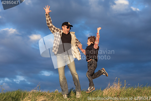 Image of Father and son walking on the road at the day time.