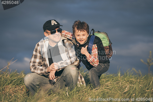 Image of Father and son walking on the road at the day time.