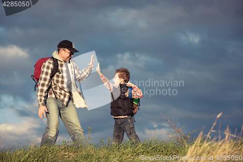 Image of Father and son walking on the road at the day time.