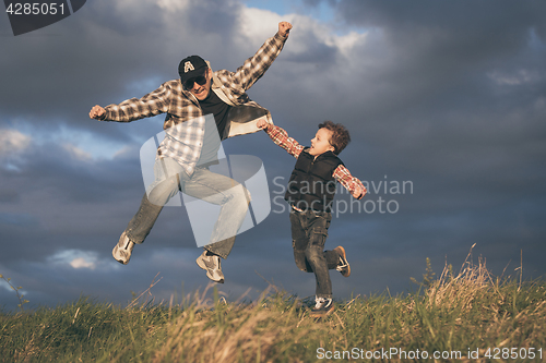 Image of Father and son walking on the road at the day time.