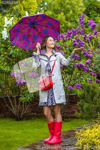 Image of Beautiful woman with an umbrella in red rubber boots