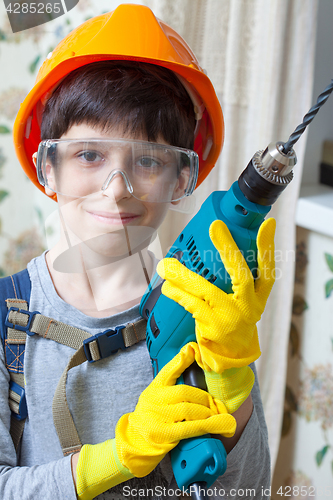 Image of boy builder in goggles and with a drill